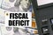 On the table are dollars, a calculator and a tag with the inscription FISCAL DEFICIT
