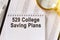 On the table are financial reports, a pen, a magnifying glass and a notebook with the inscription - 529 College Saving