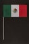 Table flag of Mexico on black background. Striped tricolor green white red. Vertical frame