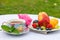 On the table in the garden is a cup of hot mint tea and a plate of assorted fruits and berries.