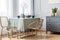Table, golden chairs and grey commode in beautiful living room interior