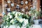 Table for guests, covered with a tablecloth, decorated with candles, transparent glass vases, fresh flowers and served with cutler