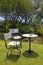 Table and iron chairs on green grass in the garden