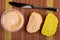 Table knife, jar with creamy fish oil, sandwich, slice of cornbread on mat. Top view