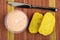 Table knife, jar with creamy fish oil, slices of cornbread on bamboo mat. Top view