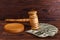 On a table the layout of the hammer of an auctioneer on a stand, next to a dollar bills.