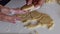 On the table lies rolled dough. Cookies are squeezed out using a mold. A woman with a knife removes it from the work surface