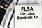 On the table lies a smartphone, a calculator and a notebook with the inscription- FLSA