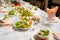 Table lined with variety of dishes from which the centerpiece is dish with banquet cutting with ham and dish with several tartlets