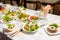 Table lined with variety of dishes from which the centerpiece is dish with banquet cutting with ham and dish with several tartlets