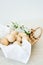 On the table is a natural wicker basket with several Easter eggs with cracks on a white napkin, painted in a fashionable pastel