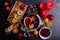 On the table is pan with mulled, a board with slices of apples and lemon, a plate with cranberries and candles.