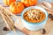 Table scene with bowl of autumn pumpkin oatmeal