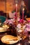 Table served for Christmas dinner, festive setting with decorations, burning candles and golden fern branches, glasses. Selected