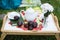 The table set for afternoon tea in a summer garden - white tea-things, book, marshmallows, flowers in a vase