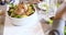 Table set with chicken and potatoes food detail. Four happy real candid friends enjoy having lunch or dinner together at