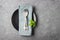 Table setting. Black plate, cutlery and napkin over gray concrete background