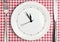 Table setting with blank clock on plate, time concept