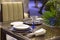 Table setting in blue color in the restaurant, plates, beautiful glasses, flowers