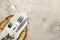 table setting. cutlery. glass, fork, knife in a white napkin and a wooden stand on a light concrete table. top view