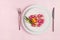 Table setting for Easter holiday. Easter eggs, duck, flower and cutlery on pink background. Top view, flat lay