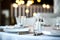 Table setting at a restaurant. Clean glass cup close up. Details of the banquet table. On the background blur are burning garlands