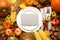 Table setting surrounded by autumn vegetables, leaves and flowers on wooden background, flat lay. Thanksgiving Day celebration