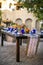 Table setting for a wedding celebration in an outdoor mission style patio with blue and orange theme, and flower decorations