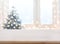 Table with space against blurred Christmas tree and decorated window