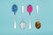 Table spoons filled with assortment of various colourful pills isolated on blue pastel coloured background. Antiobesity medication