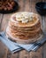 On the table on a stand made of wood cut a pile of thin pancakes