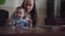 Table with tablet, mobile phone and laptop computer. Young mother with small baby boy sit on the table and open laptop