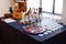 On the table there are a lot of wine glasses, a bottle and a jug of wine, and a wooden box, c