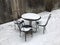 Table and three chairs in the snow