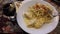 On the table, a white plate with Italian pasta and a glass of wine in the city of Gramado