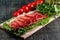 On the table is a wooden cutting board with sliced jamon, tomatoes and herbs