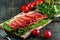 On the table is a wooden cutting board with sliced jamon, tomatoes and herbs