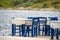 Tables and blue chairs by the seaside. Greece