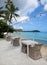 Tables and chairs on the beach with palm tree and yachts. Ocean landscape with boats as background.