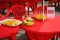 Tables under a red tablecloth with dishes of crisps, fruit and a reserved sign.