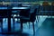 Tables and upholstered chairs in cafe in subdued dark intimate blue light