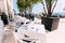 Tables with white tablecloths and chairs by the sea next to the marina with moored yachts