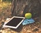 Tablet with blank screen , notebooks, apple, pencil under a tree