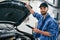 With tablet in hands. Auto mechanic working in garage. Repair service