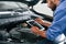 With tablet in hands. Auto mechanic working in garage. Repair service