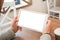 Tablet in hands closeup. Blank screen for mockup. Table, coffee, chairs in background