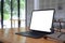 Tablet with lank display, glasses and book on wooden table.