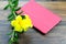 A tablet with red cover and yellow flora on wooden ground