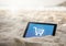 Tablet in the sand beach with Shopping trolley icon