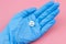 Tablet with a sleeping smiley in a hand in a medical glove on a pink background. Sleeping pills for insomnia